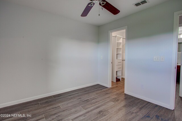 unfurnished bedroom featuring a walk in closet, ceiling fan, and hardwood / wood-style floors