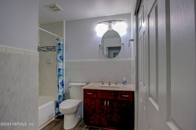 full bathroom with vanity, shower / tub combo with curtain, hardwood / wood-style floors, tile walls, and toilet