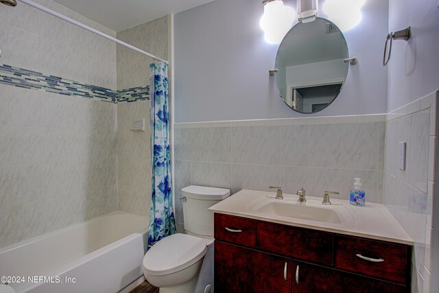 full bathroom with vanity, tile walls, toilet, and shower / tub combo