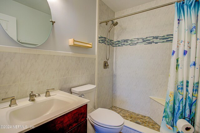 bathroom with vanity, backsplash, tile walls, a shower with curtain, and toilet