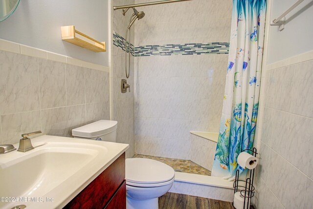 bathroom featuring toilet, hardwood / wood-style floors, vanity, tile walls, and a shower with shower curtain