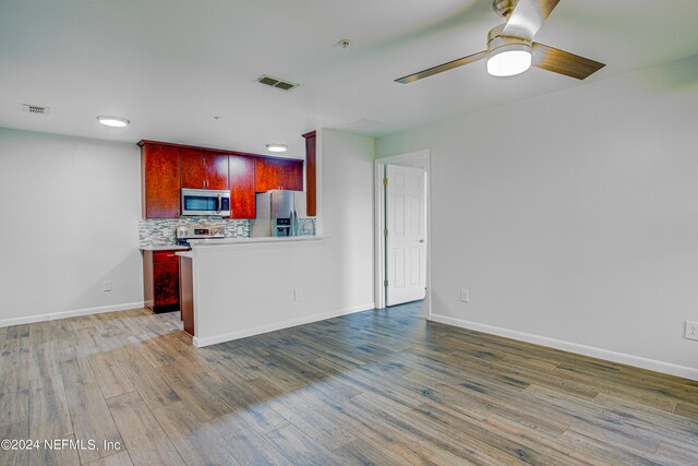 kitchen featuring wood-type flooring, ceiling fan, appliances with stainless steel finishes, and decorative backsplash