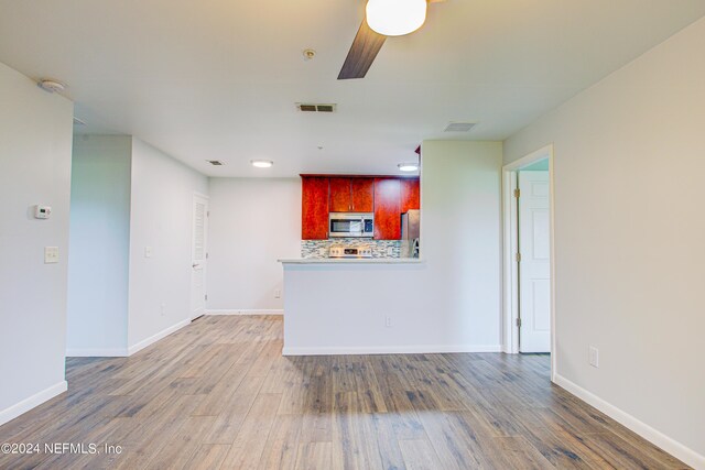 kitchen with ceiling fan, stainless steel appliances, decorative backsplash, and hardwood / wood-style flooring