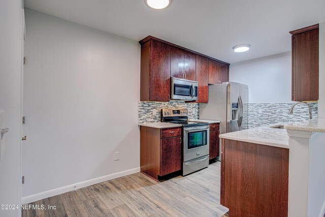 kitchen with stainless steel appliances, light hardwood / wood-style floors, tasteful backsplash, and sink