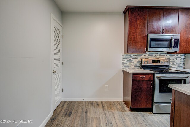 kitchen with tasteful backsplash, appliances with stainless steel finishes, and light hardwood / wood-style floors