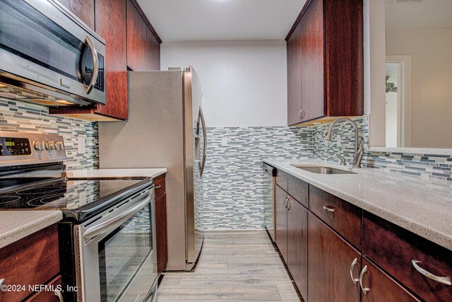 kitchen with stainless steel appliances, light hardwood / wood-style floors, tasteful backsplash, and sink