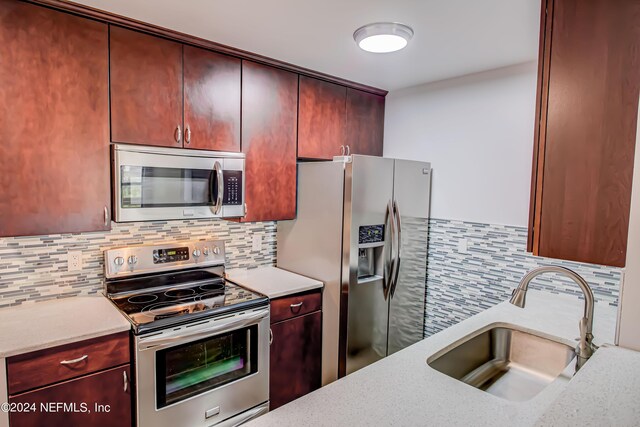 kitchen featuring stainless steel appliances, sink, and tasteful backsplash