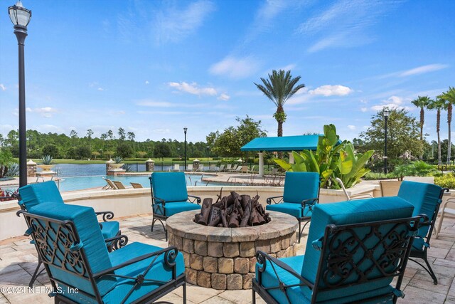 view of patio / terrace with a community pool, a water view, and an outdoor fire pit