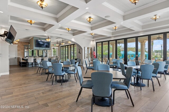 dining room with beamed ceiling, a healthy amount of sunlight, wood-type flooring, and coffered ceiling