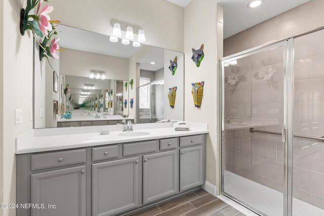 bathroom featuring a shower with door and vanity