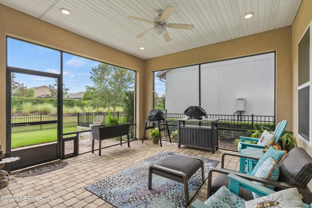 sunroom with ceiling fan and wooden ceiling