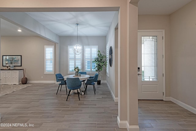 unfurnished dining area featuring a wealth of natural light, a notable chandelier, and light wood-type flooring