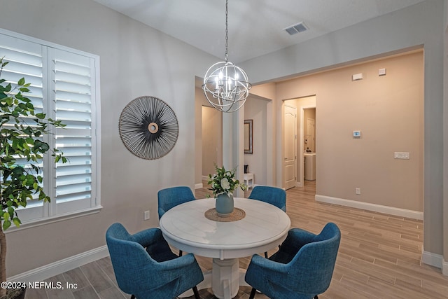 dining room with light hardwood / wood-style flooring and a notable chandelier