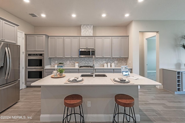 kitchen with a kitchen breakfast bar, stainless steel appliances, and a kitchen island with sink