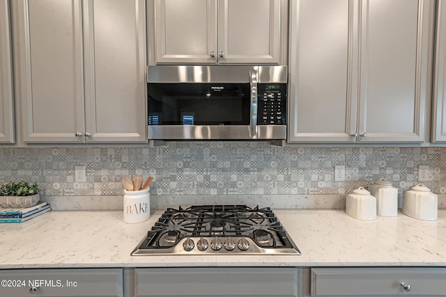 kitchen featuring light stone countertops, appliances with stainless steel finishes, tasteful backsplash, and gray cabinets