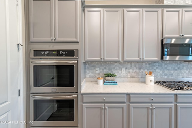 kitchen featuring light stone countertops, appliances with stainless steel finishes, and decorative backsplash