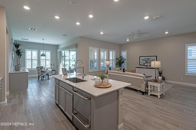 kitchen featuring a center island with sink, hanging light fixtures, sink, and a wealth of natural light