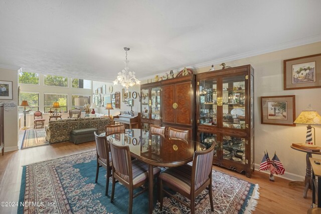 dining room featuring crown molding, light hardwood / wood-style flooring, and an inviting chandelier