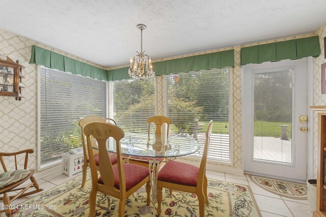 tiled dining room featuring a textured ceiling, a notable chandelier, and a healthy amount of sunlight