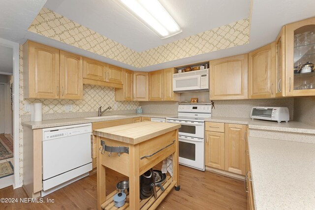 kitchen featuring light wood-type flooring, sink, light brown cabinets, and white appliances