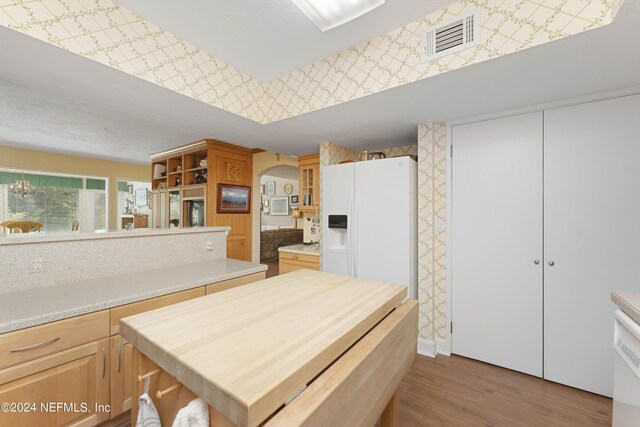 kitchen featuring white refrigerator with ice dispenser, light brown cabinetry, and light hardwood / wood-style floors