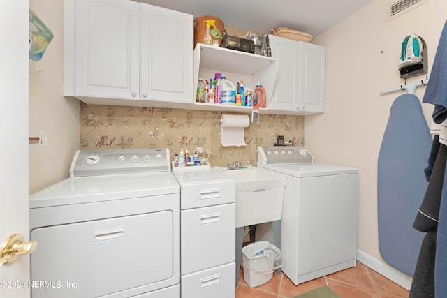 clothes washing area featuring separate washer and dryer, cabinets, and light tile patterned flooring