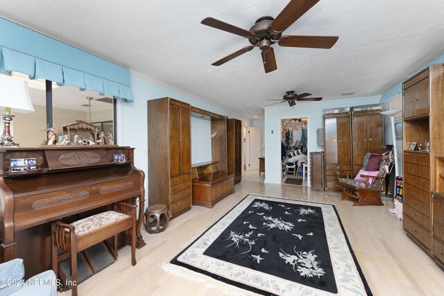 interior space with a textured ceiling, a barn door, ceiling fan, and light hardwood / wood-style flooring