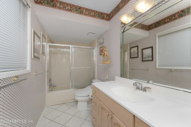 full bathroom with shower / bath combination with glass door, tile patterned flooring, toilet, and vanity