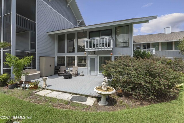 rear view of property featuring a balcony and a deck