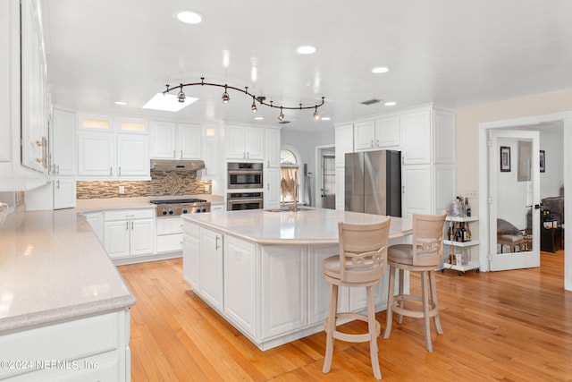 kitchen with a kitchen island, backsplash, white cabinetry, and appliances with stainless steel finishes