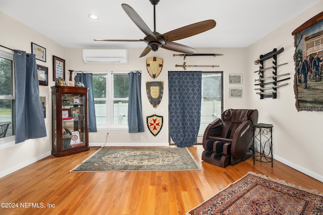 living area with hardwood / wood-style flooring, ceiling fan, and a wall mounted AC