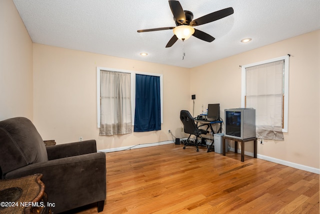 home office featuring light wood-type flooring, a textured ceiling, and ceiling fan