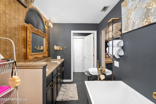 bathroom featuring a textured ceiling, a tub to relax in, and vanity