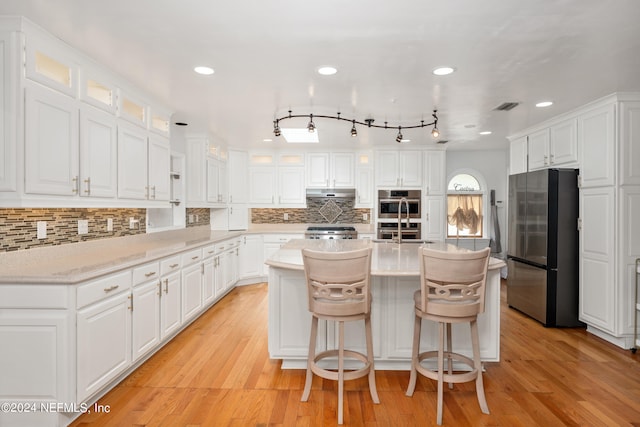 kitchen with a kitchen breakfast bar, white cabinetry, a center island, and appliances with stainless steel finishes