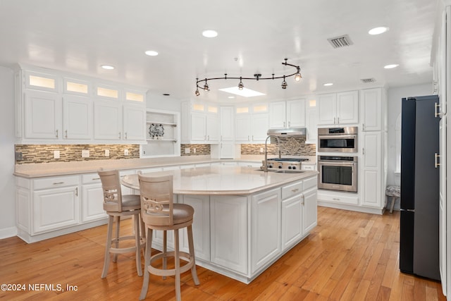 kitchen featuring white cabinets, an island with sink, light wood-type flooring, and sink