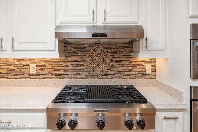 kitchen featuring white cabinetry, decorative backsplash, light stone counters, stainless steel gas stovetop, and range hood