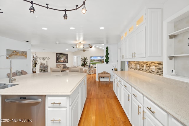 kitchen featuring white cabinets, decorative backsplash, light hardwood / wood-style floors, and stainless steel dishwasher