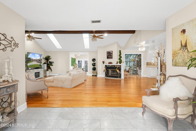 living room with light hardwood / wood-style floors, ceiling fan, lofted ceiling with skylight, and a premium fireplace