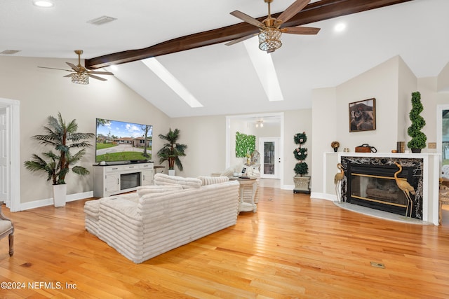 living room featuring a fireplace, vaulted ceiling with skylight, and light hardwood / wood-style flooring