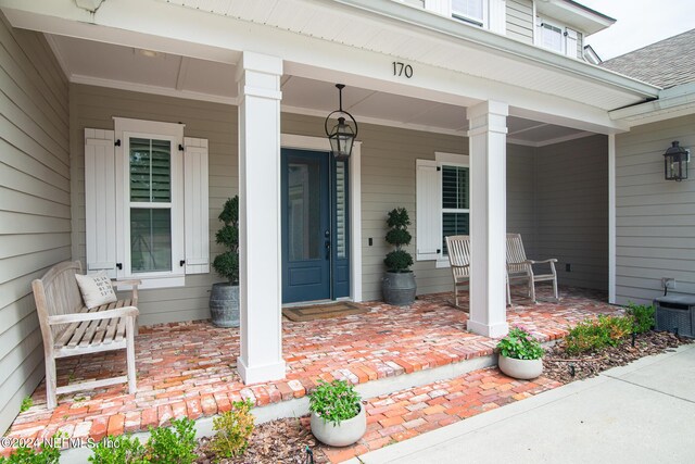 doorway to property featuring covered porch and central AC