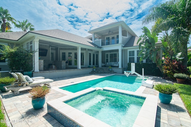 back of house with a balcony, a patio area, ceiling fan, and an in ground hot tub