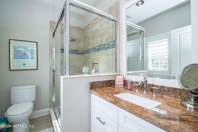 bathroom with a shower with door, vanity, and toilet