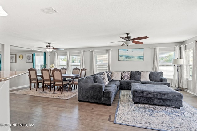 living room featuring ceiling fan, a textured ceiling, plenty of natural light, and hardwood / wood-style floors