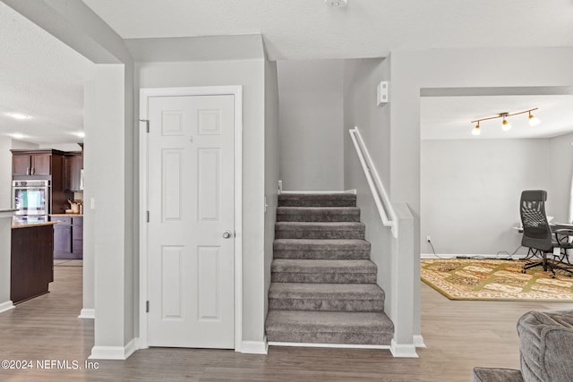 stairway with a textured ceiling and hardwood / wood-style floors