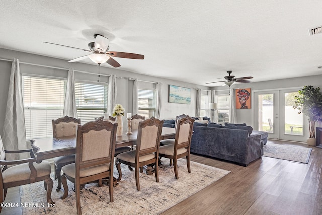 dining room with wood-type flooring, ceiling fan, french doors, and a textured ceiling