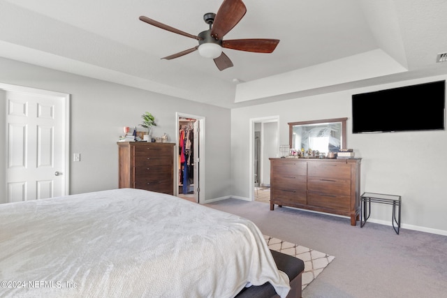 carpeted bedroom with ceiling fan, a closet, and a spacious closet