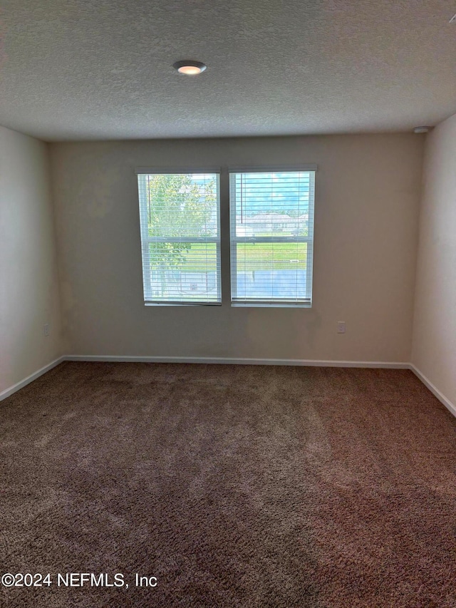 carpeted empty room featuring a textured ceiling