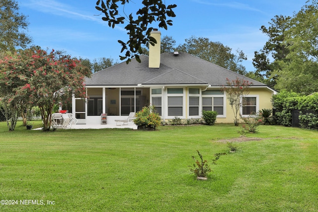 rear view of house featuring a lawn and a sunroom