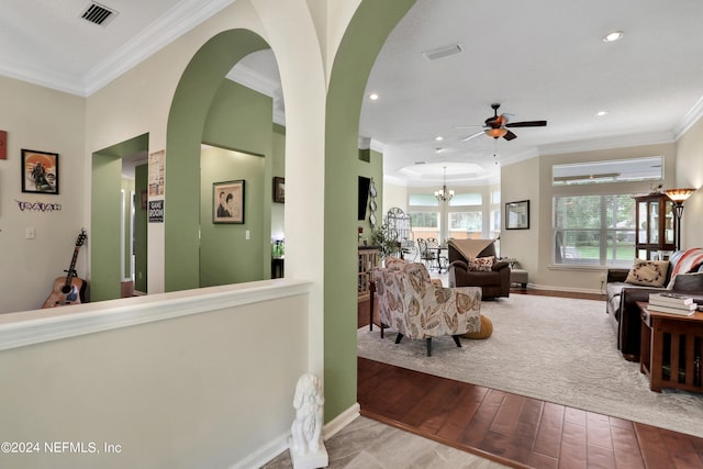 living room featuring ceiling fan with notable chandelier, ornamental molding, and hardwood / wood-style flooring