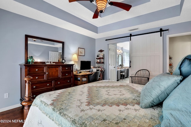 bedroom featuring a barn door, ceiling fan, and dark wood-type flooring